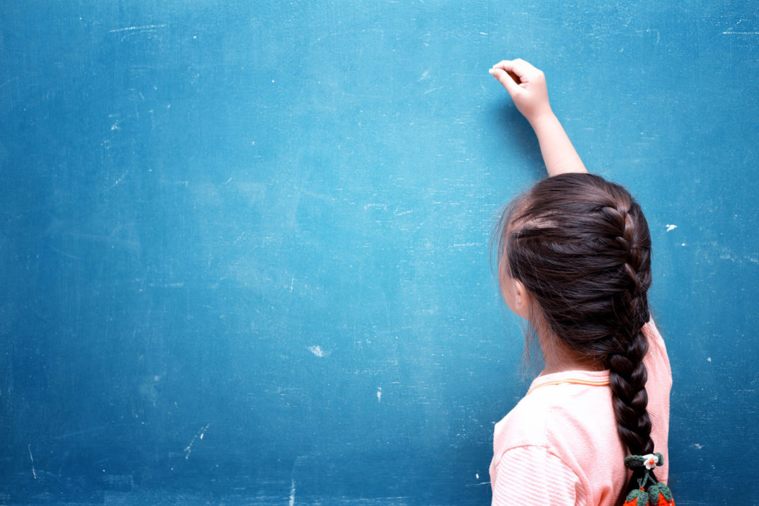 girl drawing on blank chalkboard