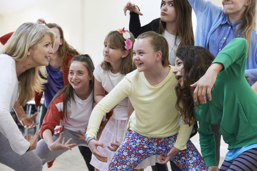 group of children with teacher enjoying drama class together