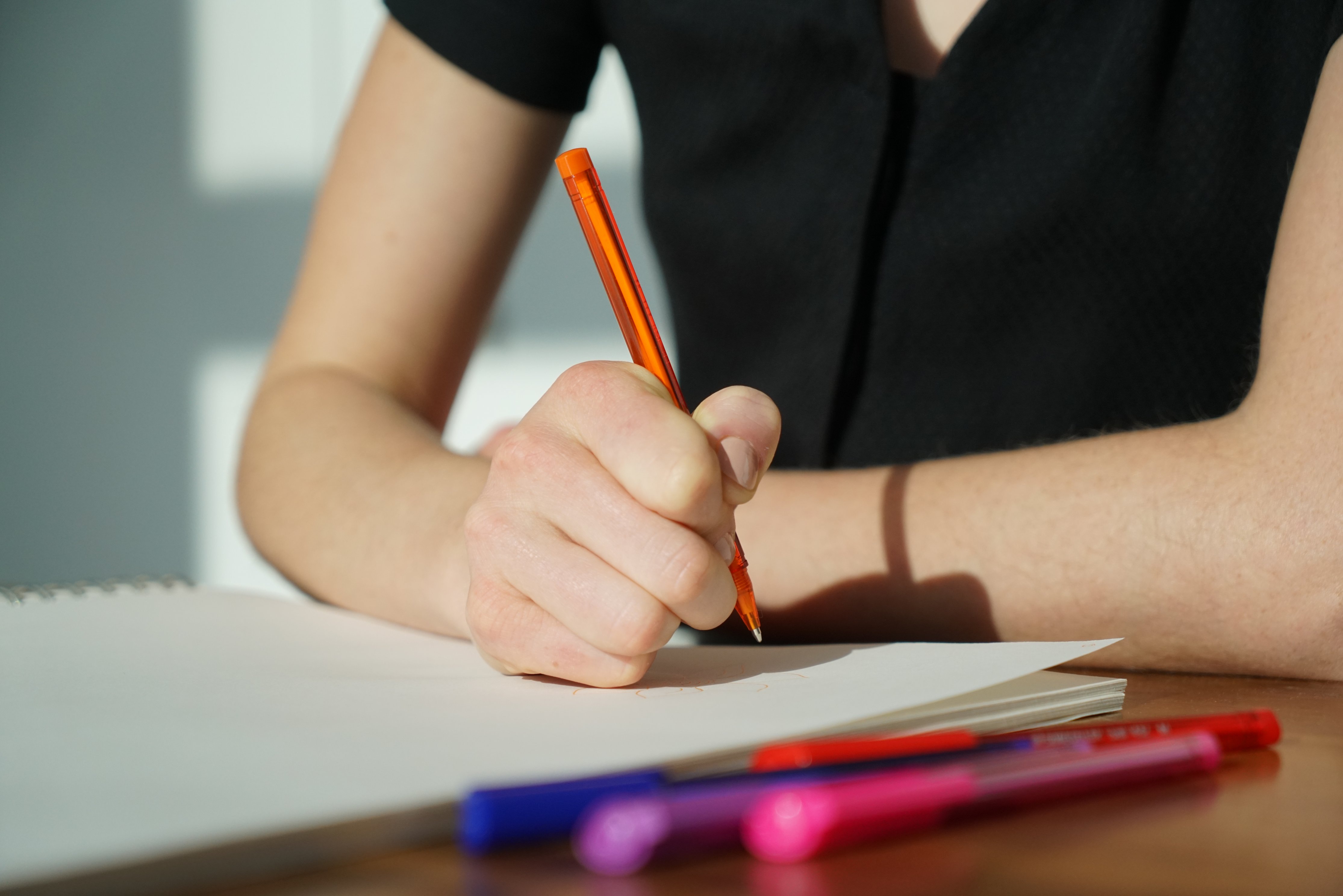 Woman writes a note with an orange pen - dishonesty in the classroom