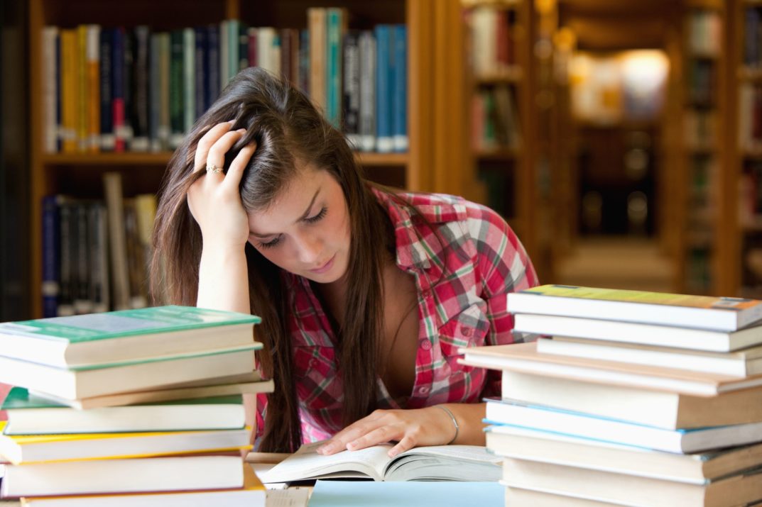 focused student surrounded by books in a library