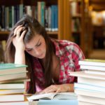 focused student surrounded by books in a library