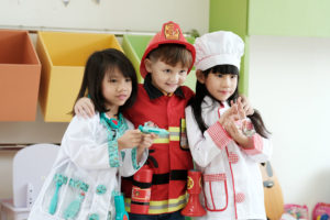 Cute boy and girls playing as fireman, doctor and cook occupatio