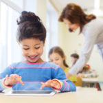 little school girl with tablet pc over classroom