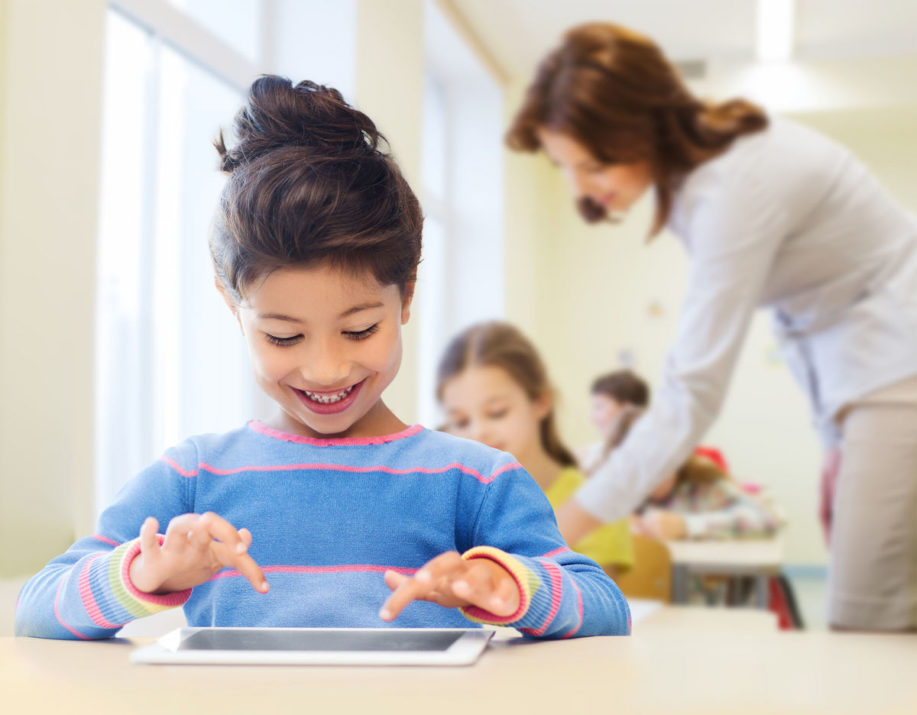 little school girl with tablet pc over classroom