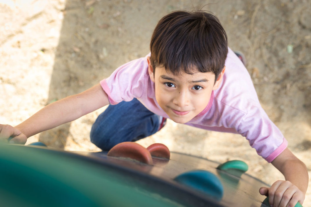 Little boy climbing up brave at playground