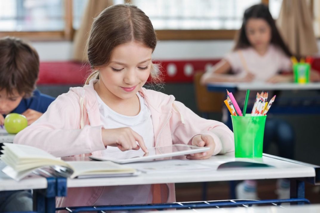 schoolgirl using digital tablet in classroom