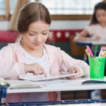 schoolgirl using digital tablet in classroom