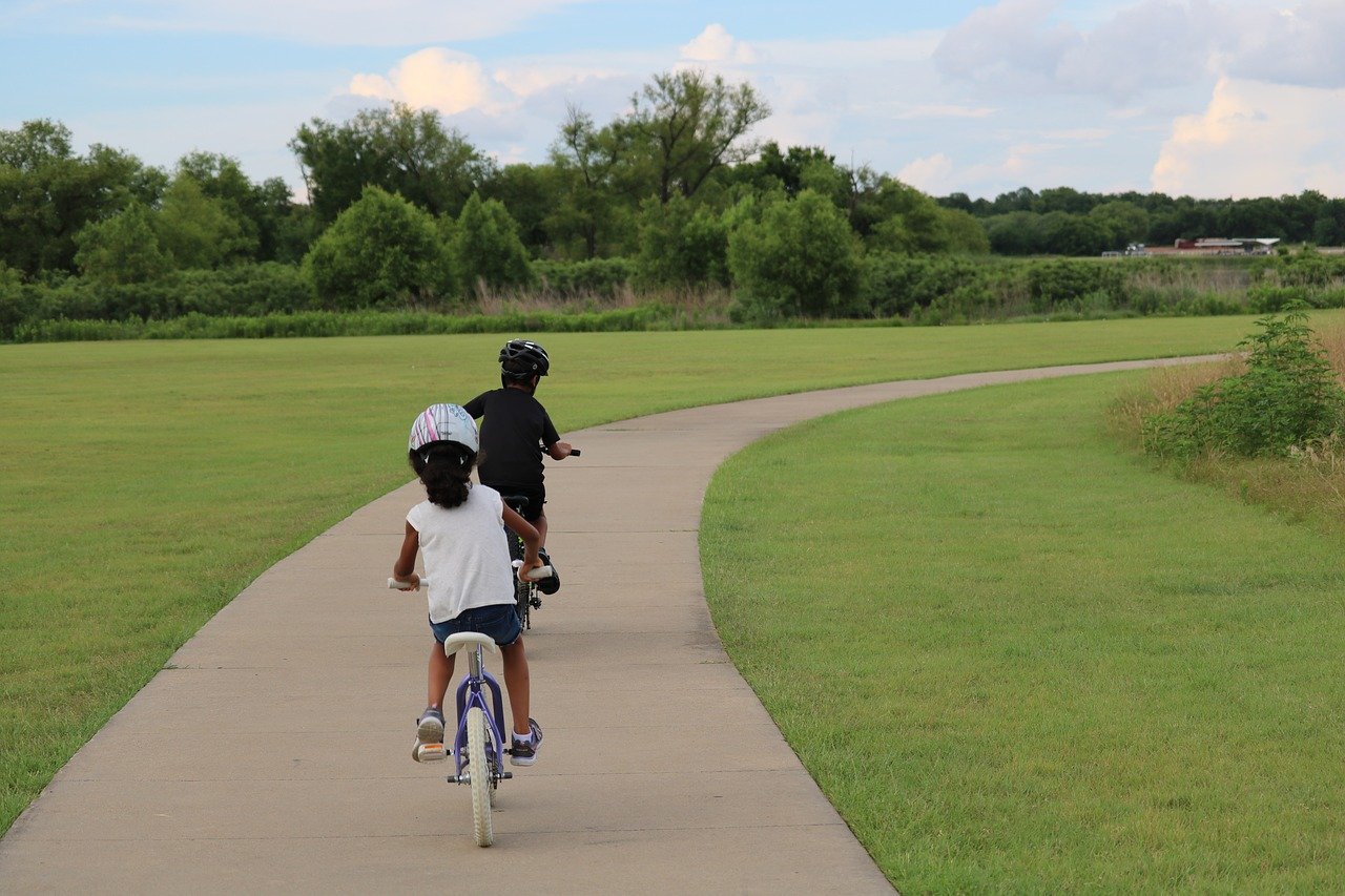 Two children on bicycles on a nature path; PE remote learning concept