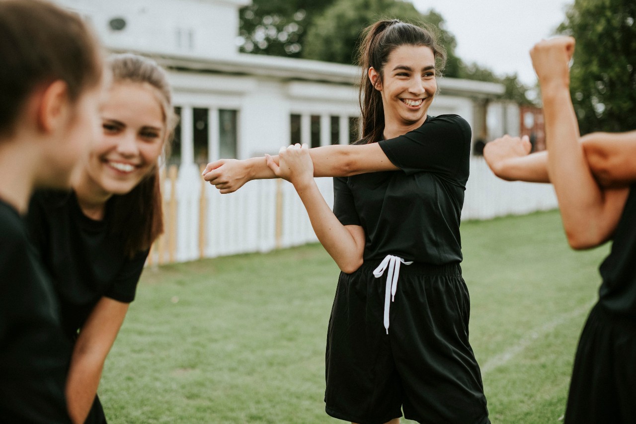 Young female soccer players smiling and stretching; PE remote learning concept
