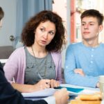 Positive woman with teenager boy discussing documents with financial adviser