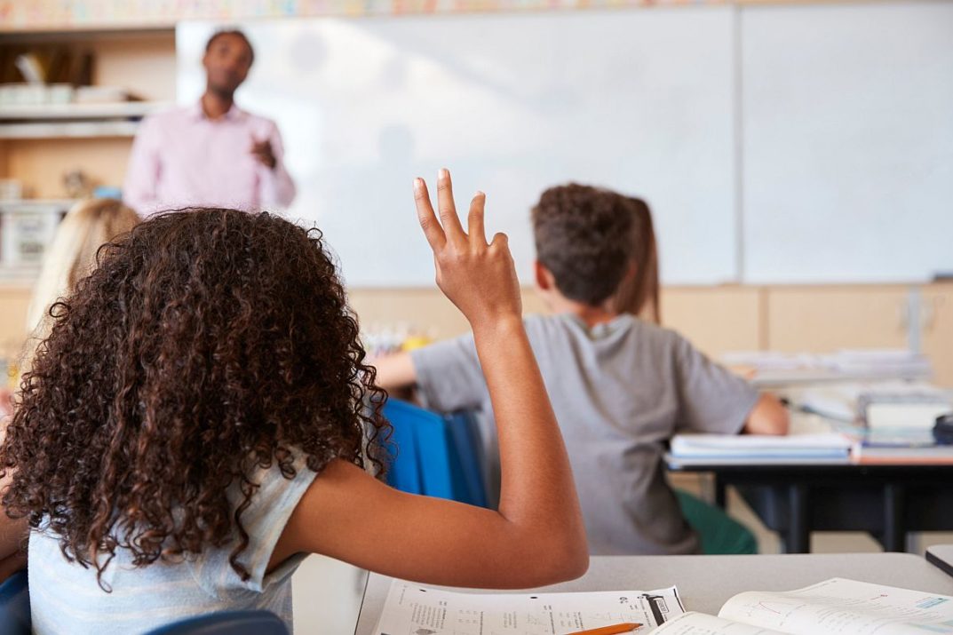 Girl raising hand to answer in an elementary school class