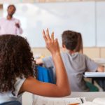 Girl raising hand to answer in an elementary school class