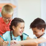 Happy elementary students sitting at desk and joyful discussing in classroom at school