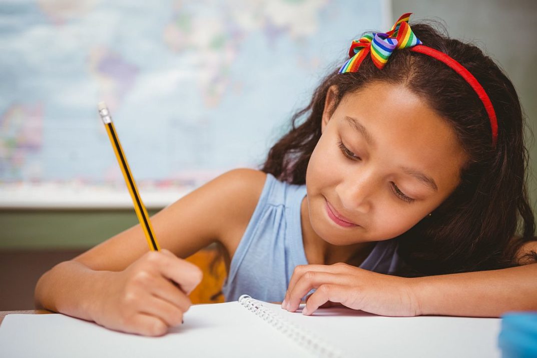 Portrait of cute little girl writing book in classroom
