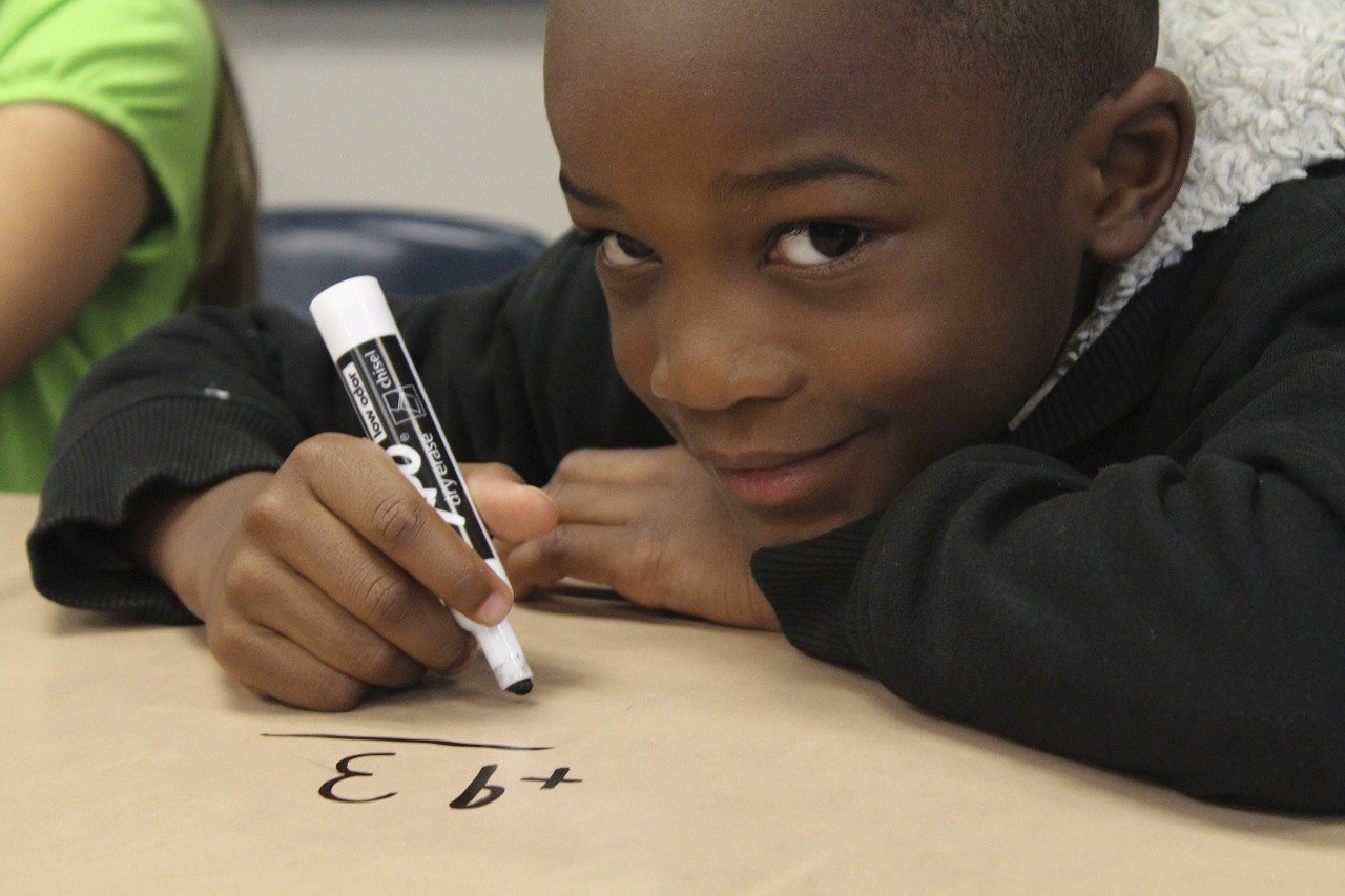 smiling child doing math homework; stacked lesson plans concept