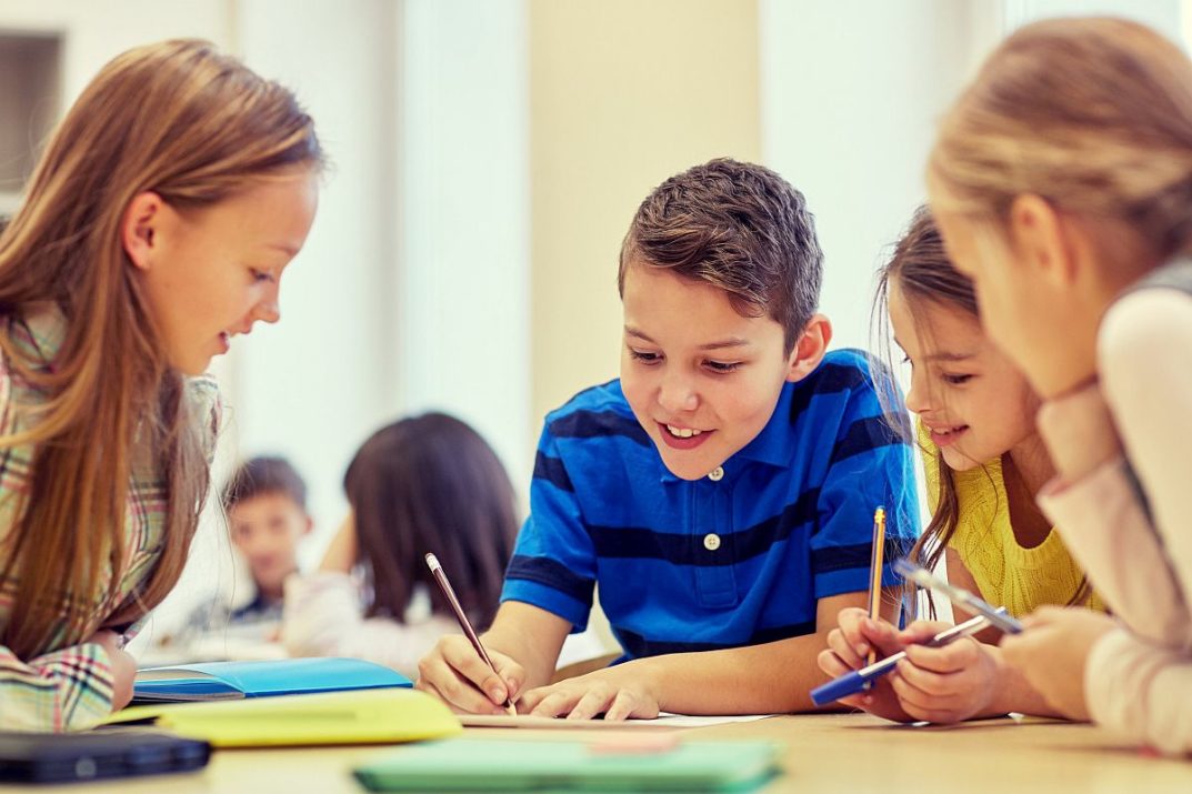 education, elementary school, learning and people concept - group of school kids with pens and papers writing in classroom