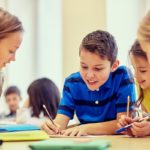 education, elementary school, learning and people concept - group of school kids with pens and papers writing in classroom