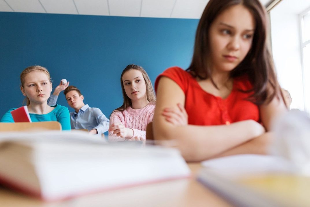 education, bullying, conflict, problem and people concept - students gossiping behind classmate back at school