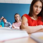 education, bullying, conflict, problem and people concept - students gossiping behind classmate back at school