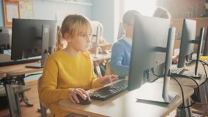 Elementary School Computer Science Classroom: Cute Little Girl Uses Personal Computer, Learning Programming Language for Software Coding. Schoolchildren Getting Modern Education.
