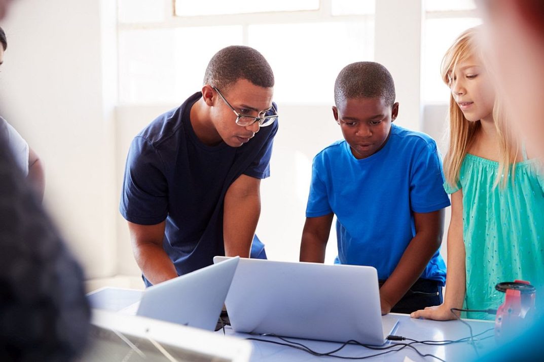 Group Of Students In After School Computer Coding Class Learning To Program Robot Vehicle