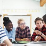 Group Of Teenage Students Collaborating On Project In Classroom