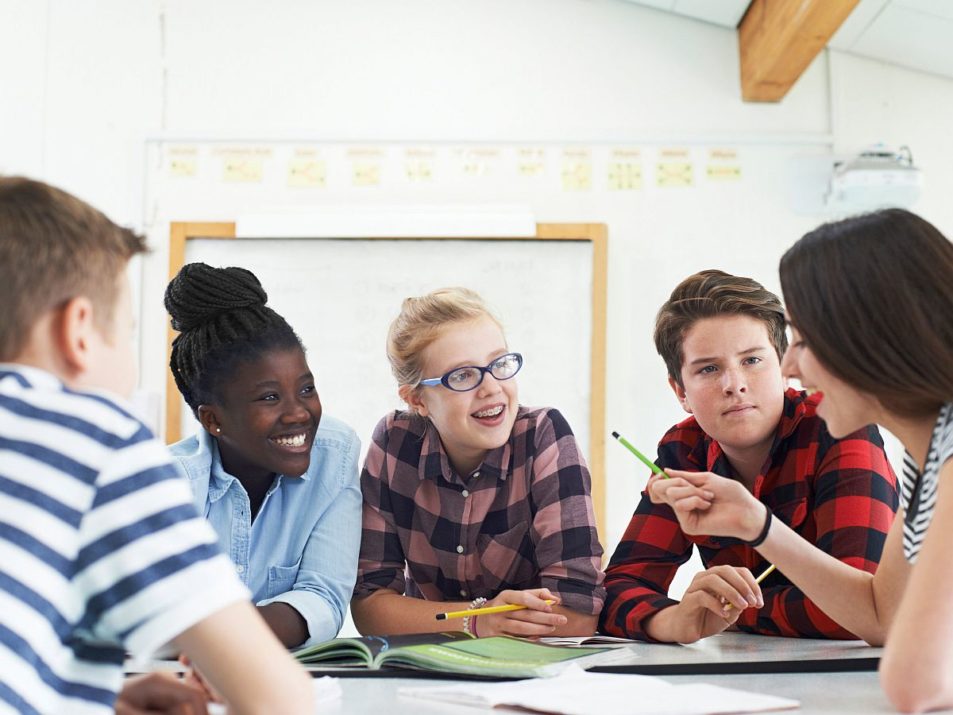 Group Of Teenage Students Collaborating On Project In Classroom