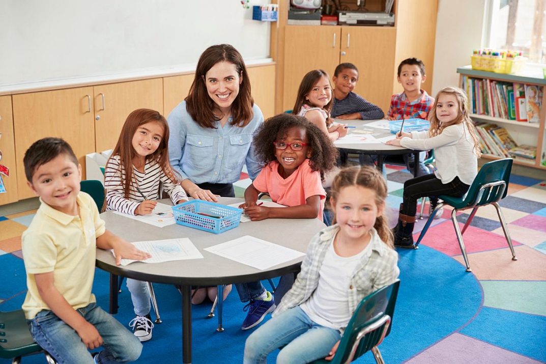 Female school teacher and kids in class smiling to camera