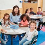 Female school teacher and kids in class smiling to camera