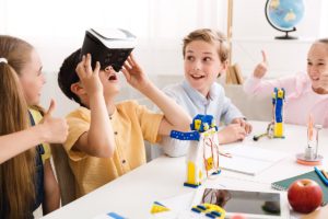 Happy school boy using VR glasses at technology lesson for kids at school