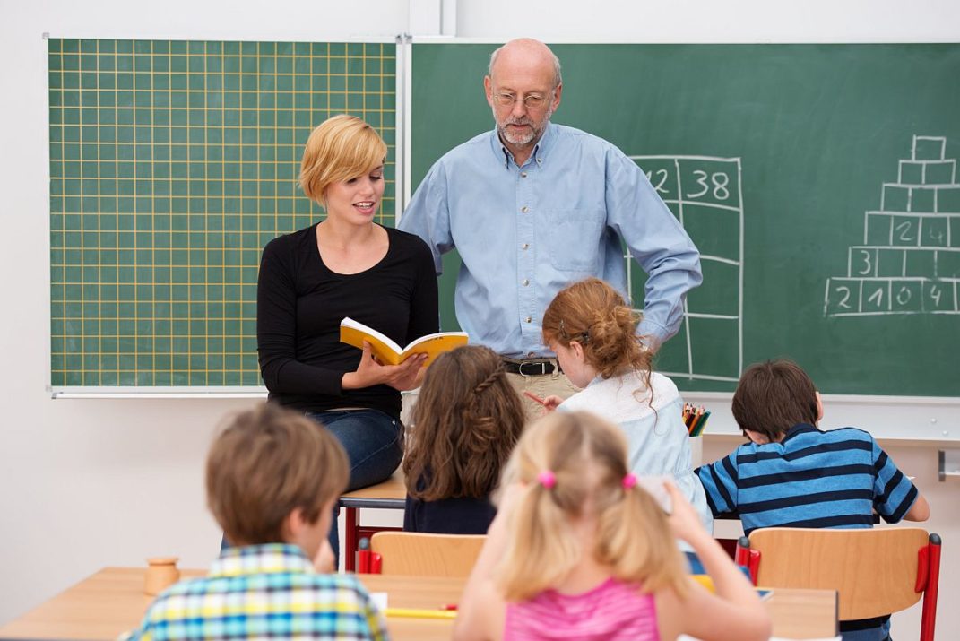 Teacher with his student teacher standing in front of a class; student teacher concept