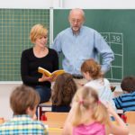 Teacher with his student teacher standing in front of a class; student teacher concept