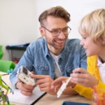 Teacher smiling with young student; paraeducators and teachers concept