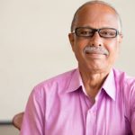 kind teacher in pink shirt in front of a blackboard; teaching in a different state concept