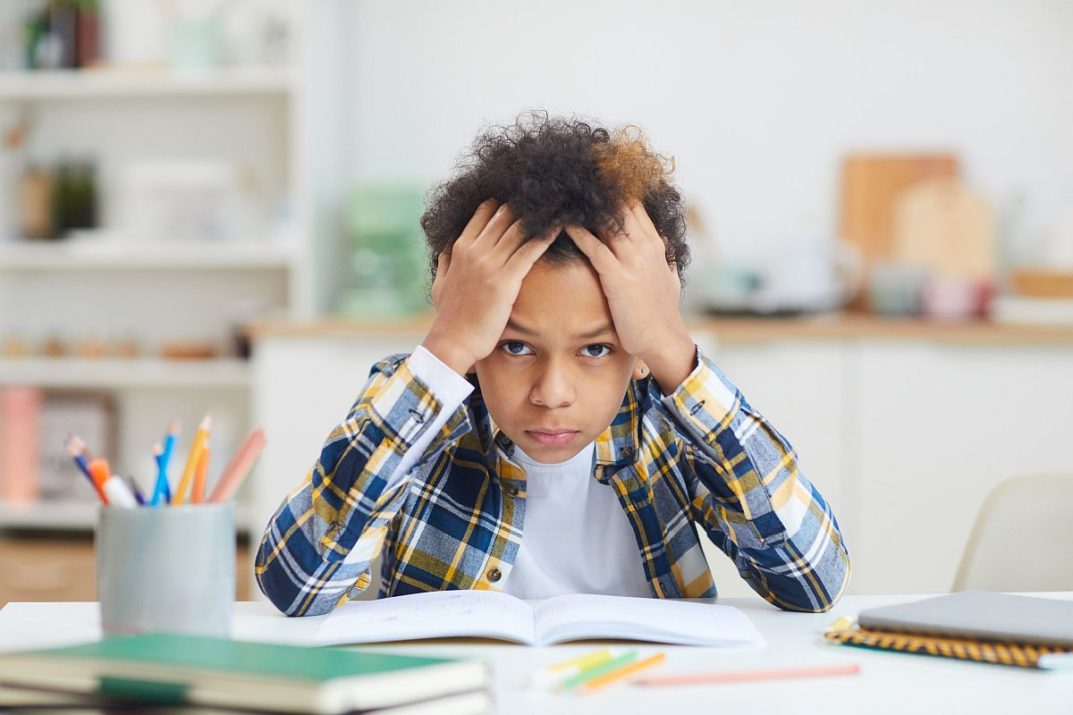 Boy sitting at table, with open book; self-calming strategies for students concept