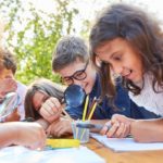 Several children in outdoor classroom using magnifying glasses; botany lessons concept