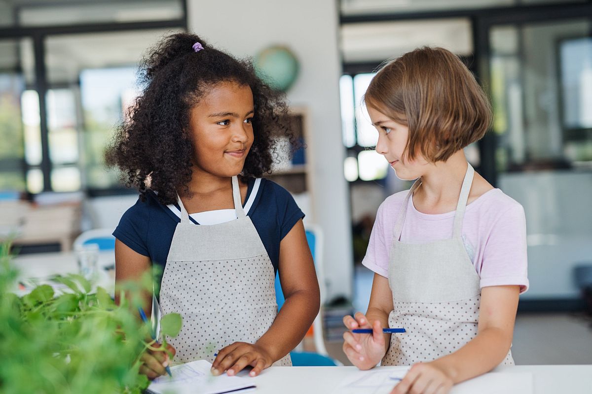 Two young girls working together in a classroom with plants; botany lessons concept