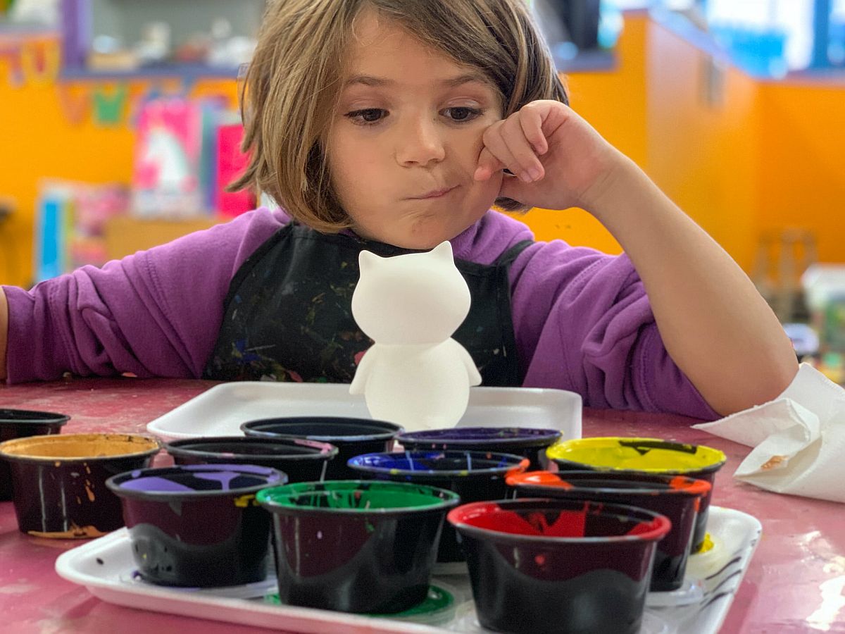 Child at table with different color paints; classroom management concept.