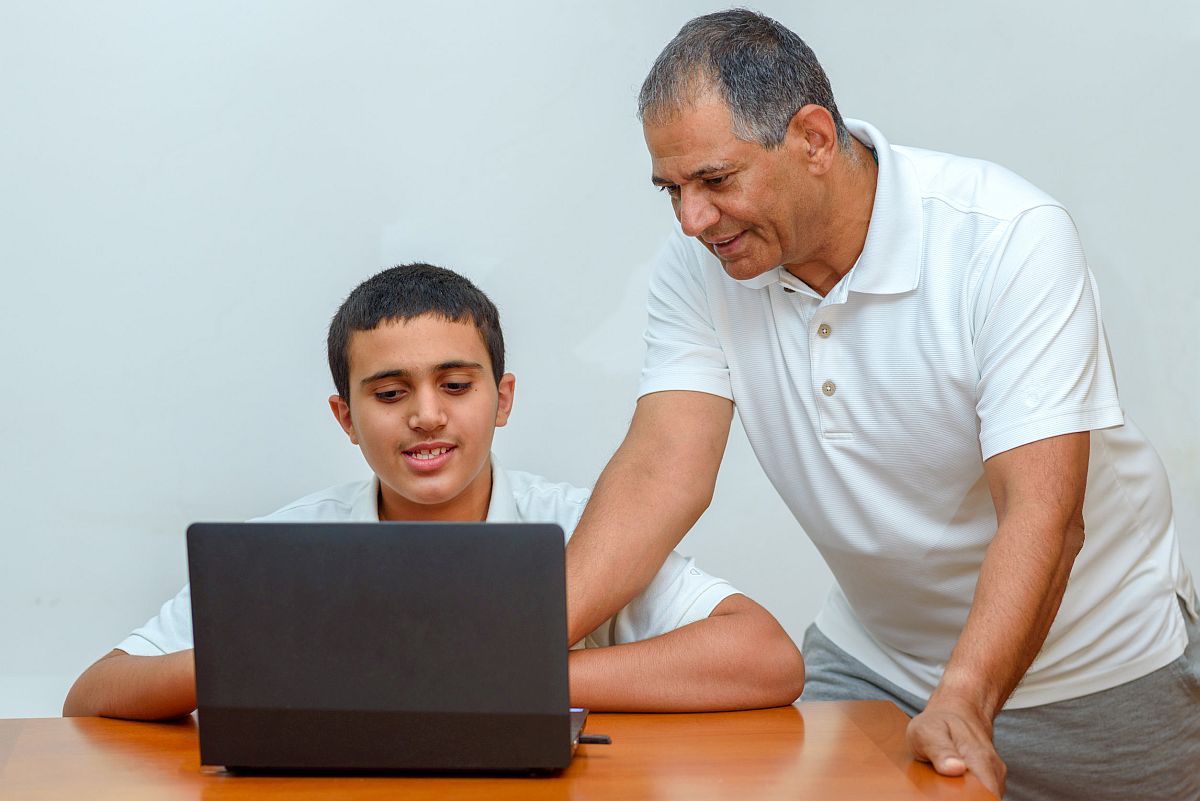 Older man and teenage boy looking at a laptop; students with learning disabilities concept