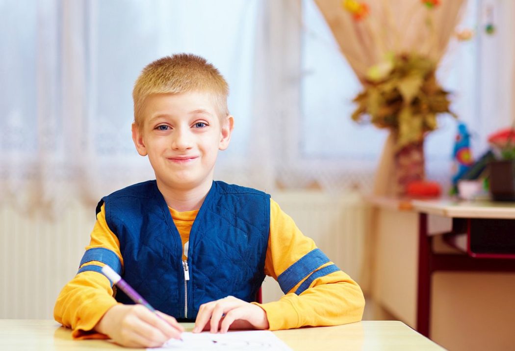 Child writing at a desk; classroom management concept