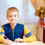 Child writing at a desk; classroom management concept