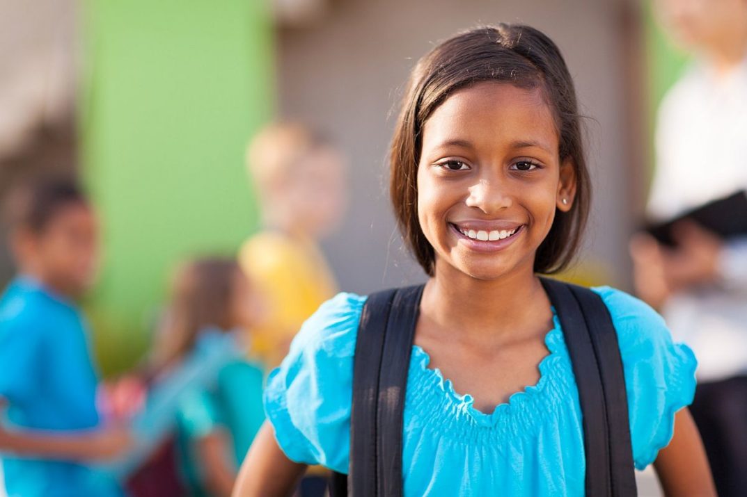 Smiling girl with other children around her in a blurred background; cultures and ethnicities concept