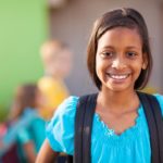 Smiling girl with other children around her in a blurred background; cultures and ethnicities concept