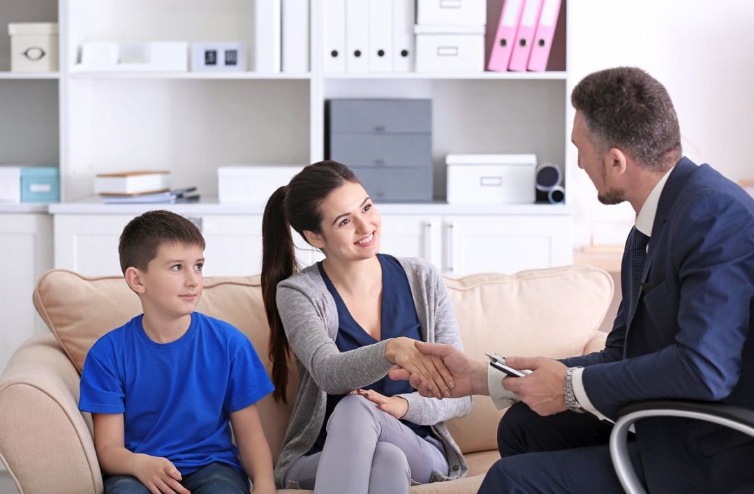 Smiling woman shaking hands in meeting with child at school office; individualized education program concept