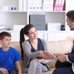 Smiling woman shaking hands in meeting with child at school office; individualized education program concept