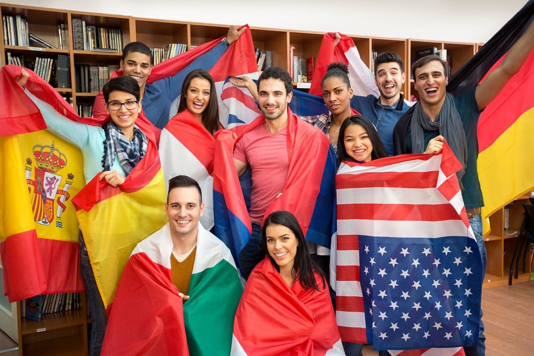 Group of students in classroom, with large flags from different countries; English Language Learners concept