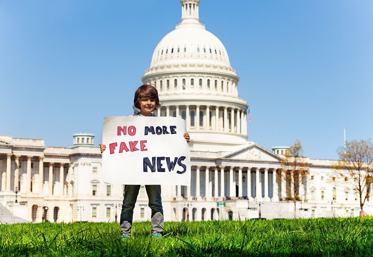 Child holding sign that reads no more fake news; voting lesson plans concept