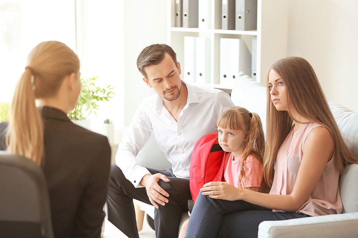 Young family sitting on sofa in discussion with professional; social emotional concept