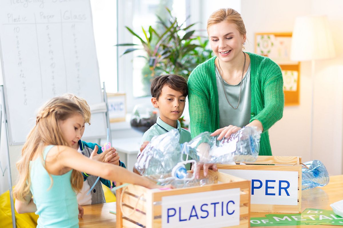Teacher and children sorting plastic recyclables; climate change lesson plans concept
