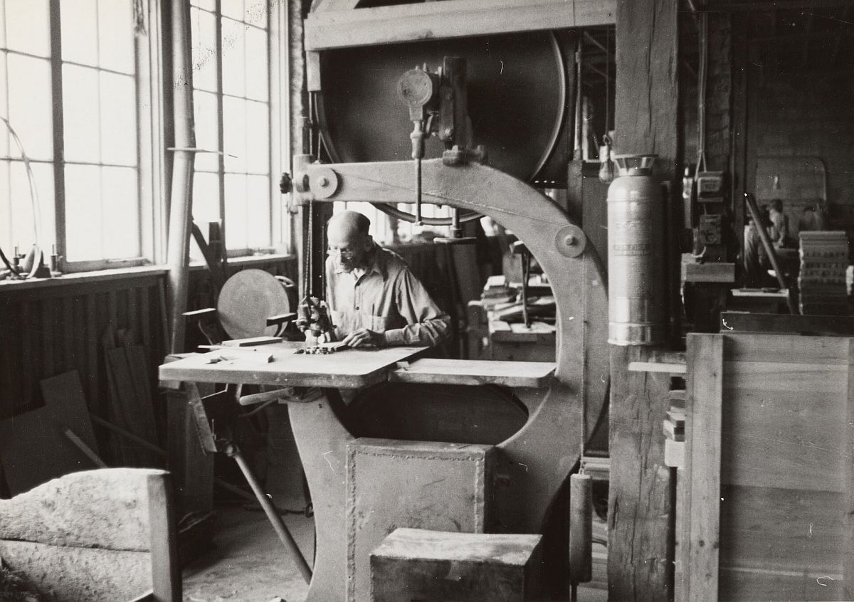 archival black and white photo of a worker operating factory equipment; labor history lesson plans concept
